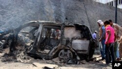 Yemenis inspect the scene of a car bomb attack that killed a Yemeni senior official in the southern port city of Aden, Yemen, Sunday, Dec. 6, 2015. A huge explosion killed the governor of Yemen's southern Aden province and six of his bodyguards.