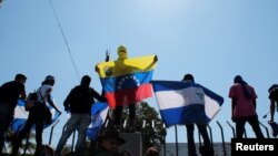 FILE - Anti-government protesters hold flags and shout slogans to riot police during a demonstration against Nicaraguan President Daniel Ortega's government in Managua, Nicaragua, March 30, 2019.