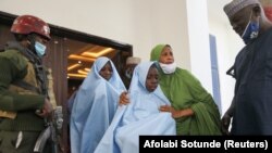 Seorang pejabat memeluk seorang gadis yang diculik dari sebuah sekolah asrama di negara bagian Zamfara, Nigeria barat laut, saat dia menuju pemeriksaan kesehatan setelah dibebaskan di Zamfara, Nigeria, 2 Maret 2021. (Foto: REUTERS/Afolabi Sotunde)