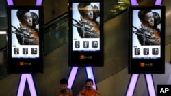 Children use smartphones near monitors displaying a Chinese action movie "Wolf Warrior 2" at a cinema in Beijing, Aug. 10, 2017. The patriotic film reportedly inspired by evacuations of Chinese civilians in Libya and Yemen is becoming one of China's bigge