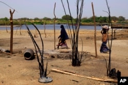 FILE - Chadian women walk past destroyed homes in the Lake Chad shore village of N'Gouboua, March 5, 2015, following a scorched-earth attack by Boko Haram militants.