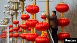 A man hangs lanterns along a street ahead of the Chinese Lunar New Year in Xuchang, Henan province, China, January 15, 2017. 