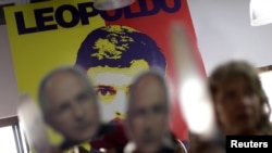 People hold portraits of opposition leader Antonio Ledezma in front of a wall with a portrait of opposition leader Leopoldo Lopez during a news conference at the Venezuelan coalition of opposition parties (MUD) headquarters in Caracas, Venezuela, Aug. 1, 2017.