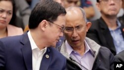 Former chief of the Philippine PNP-CIDG and now Mayor Benjamin Magalong, right, talks to Justice Secretary Menardo Guevarra at the resumption of the Senate probe Oct. 9, 2019 in suburban Pasay city south of Manila, Philippines. 