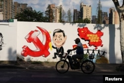 A man rides a bicycle next to a mural showing an image of Chinese President Xi Jinping along a street in Shanghai, China September 28, 2018. REUTERS/Aly Song