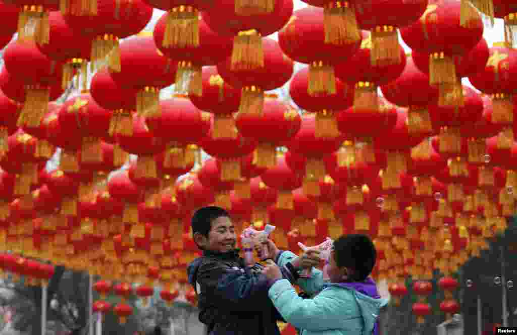 Children play with bubble toy guns under Chinese lunar New Year decorations at a park in Beijing. According to the Chinese lunar calendar, the New Year, which welcomes the Year of the Horse, falls on January 31. 