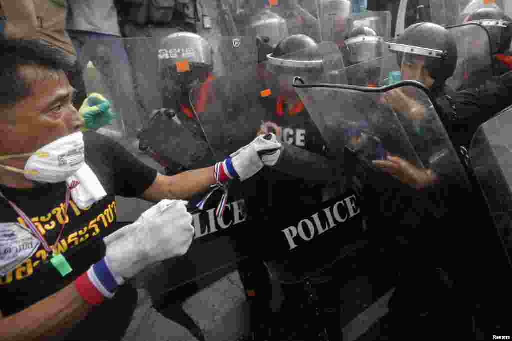 Seorang demonstran anti-pemerintah bentrok dengan polisi di sebuah barikade dekat gedung pemerintah di Bangkok (25/11).