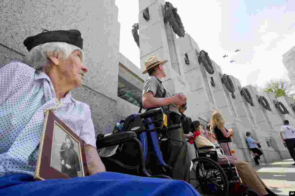 Holding a World War II-era photograph of herself, WWII veteran Elizabeth Copp, 96, who was a Sergeant in the Women's Army Corps during World War II, watches as World War II aircraft fly over the World War II Memorial in Washington, May 8, 2015, in honor of the 70th anniversary of Victory in Europe Day (VE Day).