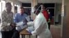 Staff hand out health forms to arriving passengers, Lungi international airport, Sierra Leone, Feb. 3, 2015. (Nina deVries/ VOA)