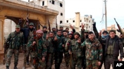 In this photo released Feb. 16, 2020 by the Syrian official news agency SANA, Syrian army soldiers flash the victory sign in the Rashideen neighborhood, in Aleppo province, Syria.