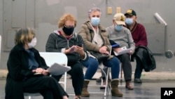 FILE - In this Jan. 20, 2021, file photo, people that received a COVID-19 vaccine socially distance as they wait the required fifteen minutes to monitor for adverse reactions after getting the shot at Fair Park in Dallas.