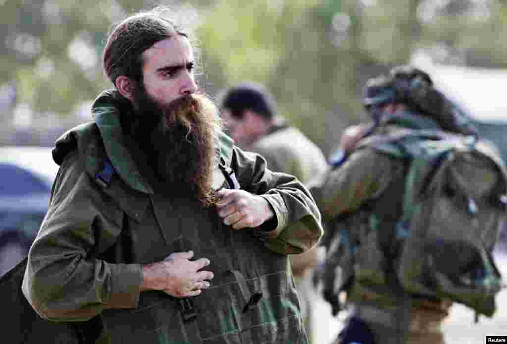 An Israeli army reservist adjusts his gear in a staging area outside the Gaza Strip, July 18, 2014. 