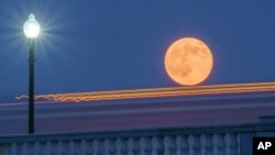 In this 2014 file photo, traffic streaks by the supermoon as it rises behind the Memorial Bridge in Washington, Saturday, July 12, 2014. (AP Photo/J. David Ake)