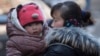 FILE - A Chinese woman cuddles her child in Beijing, China, March 6, 2014. China announced Thursday it was ending its long-standing one-child policy and will now allow all couples to have two children.