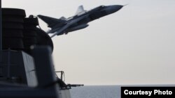 FILE - A Russian aircraft makes a flyover pass near the USS Donald Cook in the Baltic Sea, April 12, 2016.