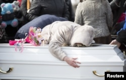 A woman reacts during a funeral of a victim of a shopping mall fire at a cemetery in Kemerovo, Russia March 28, 2018.