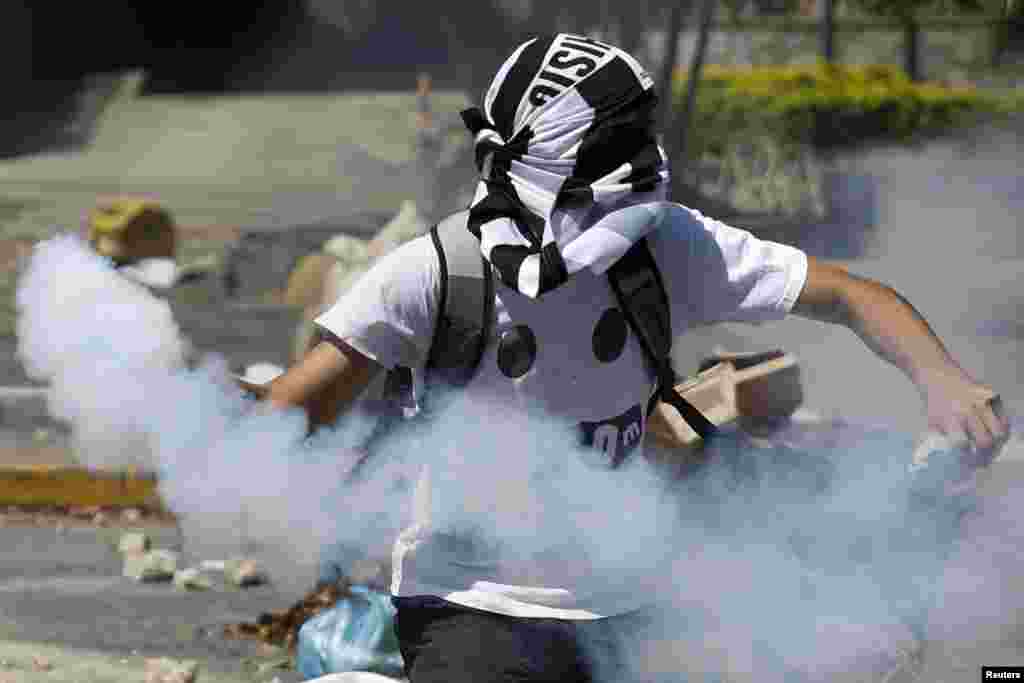 Seorang demonstran anti-pemerintah melemparkan kaleng berisi gas air mata ke arah polisi dalam aksi protes di Caracas, Venezuela.&nbsp;