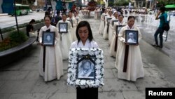 Para pengunjuk rasa memegang potret para perempuan Korea yang dipaksa menjadi budak seks oleh tentara Jepang selama Perang Dunia Kedua, dalam upacara penghormatan bagi Lee Yong-nyeo, di pusat Seoul (14/8). Lee, salah seorang mantan budak seks tentara Jepang jaman PD II, dilaporkan meninggal dunia hari Minggu (11/8).