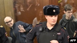 Penyair Rusia Artyom Kamardin (kiri) dan Yegor Shtova (kanan) berdiri di dalam ruang kaca untuk terdakwa dalam sidang pembacaan vonis di sebuah pengadilan di Moskow, Kamis, 28 Desember 2023. (Foto: Alexander Nemenov/AFP)