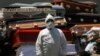 An employee of Xochimilco's crematorium waits for a corpse, suspected to have died of the new coronavirus, in Mexico City, May 4, 2020. He is standing next to pile of discarded coffins that contained people who died of COVID-19 disease.