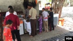 Yazidis are seen gathered outside the Lalish temple, enjoying shade, water and ice cream. Lalish, Iraq, July 31, 2015. (Photo - S. Behn/VOA)