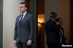 French President Emmanuel Macron accompanies a guest after a meeting at the Elysee Palace in Paris, Jan. 12, 2018.