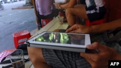 FILE - A customer uses his tablet to access the Internet at a 'wifi coffee shop' in downtown Hanoi.