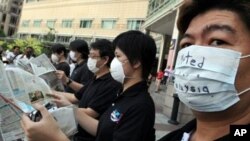 Masked activists with upside down newspapers silently protest restrictions on Malaysian media, Aug. 2010. Prime Minister Najib says he will review publishing laws (file photo).