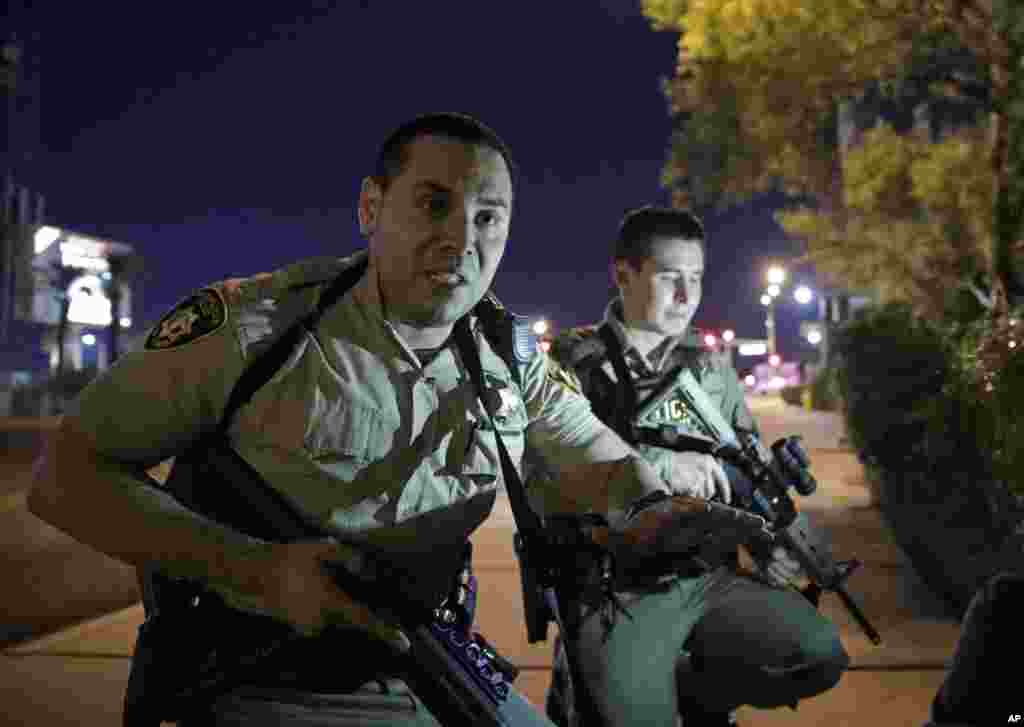 Police officers advise people to take cover near the scene of the shooting near the Mandalay Bay resort and casino on the Las Vegas Strip, Sunday, Oct. 1, 2017, in Las Vegas.