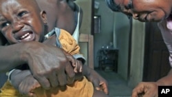 Aliyatu Abdulai (R), a Sierra Leonean Maternal and Child Health Aide, administers a vaccine to a child in the village of Sembehun, outside the town of Bo, in the southeast region of the West African country, which is supported by the GAVI Alliance that fu