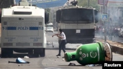 A protester throws stones at police vehicles in the Kurdish dominated southeastern city of Diyarbakir, Turkey, September 13, 2015. 