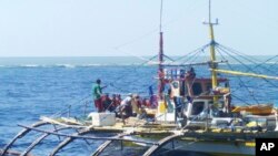 In this photo provided by Renato Etac, Chinese Coast Guard members, wearing black caps and orange life vests, approach Filipino fishermen as they confront them off Scarborough Shoal at South China Sea in northwestern Philippines, Sept. 23, 2015.