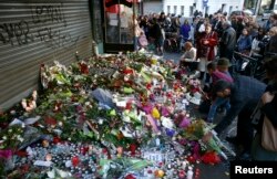 People pay their respect at one of the attack sites in Paris, Nov. 15, 2015.