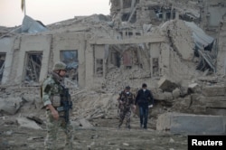 FILE - Afghan security forces and NATO troops investigate at the site of an explosion near the German consulate in Mazar-i-Sharif, Afghanistan, Nov. 11, 2016.