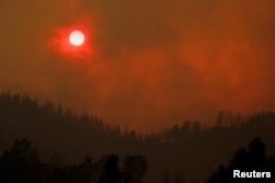 The setting sun is turned red by the smoke from the Carr Fire burning in the hills west of Redding, Calif., July 27, 2018.
