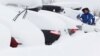 Un homme déneige sa voiture à Saint-Chaffrey, France, le 1er mars 2018.