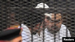 Political activists Ahmed Maher, Ahmed Douma (L) and Mohamed Adel (R) of the April 6 movement look on from behind bars in Abdeen court in Cairo, Egypt, Dec. 22, 2013.
