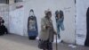 A bypasser looks at graffiti works by Yemeni artist Haifa Subay in Sanaa. The murals depict different facets of the conflict in Yemen, such as the horror of land mines and the demand for girls' education.