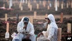 Para pekerja beristirahat di tengah kesibukannya di Pemakaman Rorotan yang diperuntukkan bagi mereka yang meninggal dunia akibat COVID-19, di Jakarta, Kamis, 1 Juli 2021. (Foto: AP)