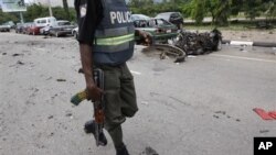 Un policier nigérian passant à côté de l'épave d'une voiture brûlée dans l'une des explosions d'Abuja