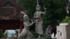 A man walks pass by a statue of Moni Mekhala, goddess of the seas, and Ream Eyso, storm demon, inside Royal University of Fine Art on May 28, 2015. (Nov Povleakhena/VOA Khmer)