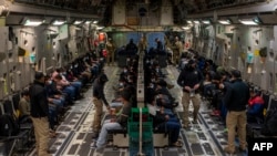 Kjo fotografi e shpërndarë nga Departamenti i Mbrojtjes tregon migrantë pa dokumente që presin të dëbohen. Aeroportin Ndërkombëtar Tucson, Arizona, 23 janar 2025. (Foto AFP / DVIDS / Departamenti i Mbrojtjes / Aeroplani i Lartë Devlin Bishop)