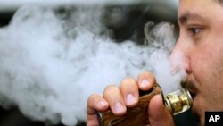 A man breathes vape from an e-cigarette at a vape shop in London, Aug. 17, 2018.