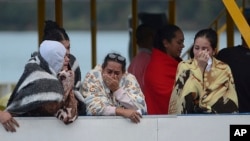 People who survived a sunken ferry, cry as they wait for more information about their missing friends and relatives, at a reservoir in Guatape, Colombia, June 25, 2017.