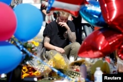 FILE - Bry Thompson wipes away tears at a makeshift memorial in the middle of Las Vegas Boulevard following the mass shooting in Las Vegas, Nevada, Oct. 4, 2017.