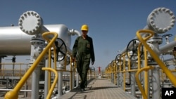 FILE - An oil technician makes his way to the oil separator facilities in Iran's Azadegan oil field. Falling oil prices are depressing living standards in the Islamic Republic. 