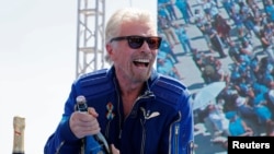 Richard Branson prepares to spray champagne after flying with a crew in Virgin Galactic's passenger rocket plane VSS Unity to the edge of space, at Spaceport America, near Truth or Consequences, New Mexico, July 11, 2021.