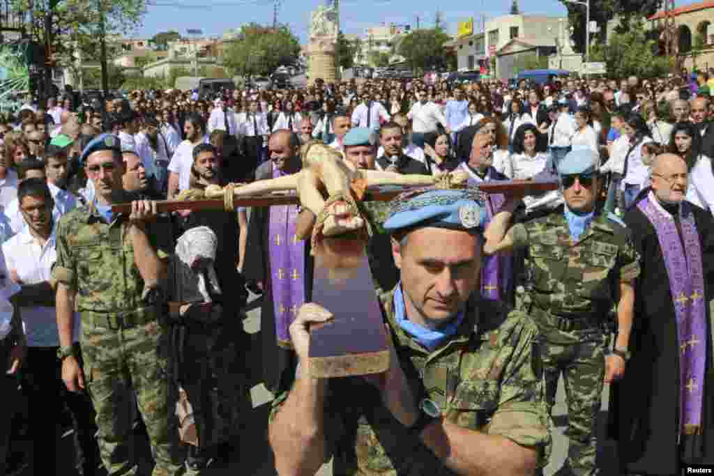 Serbian and Spanish U.N. peacekeepers carry a cross with a statue of Jesus Christ during a Good Friday ceremony in Kalayaa, Marjayoun countryside in south Lebanon, April 18, 2014. 