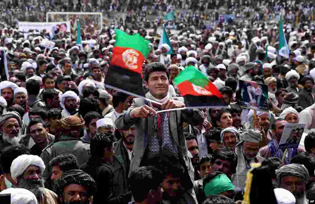 Seorang pendukung kandidat presiden dan mantan menteri luar negeri Zalmai Rassoul (tengah) melambai-lambaikan dua bendera nasional Afghanistan dalam sebuah kampanye pemilu di Herat (30/3).&nbsp;(AP/Massoud Hossaini)