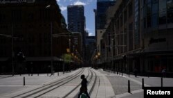 A pedestrian wearing a protective face mask crosses tram lines in the city center during a lockdown to curb the spread of COVID-19 in Sydney, Australia, Sep 24, 2021.